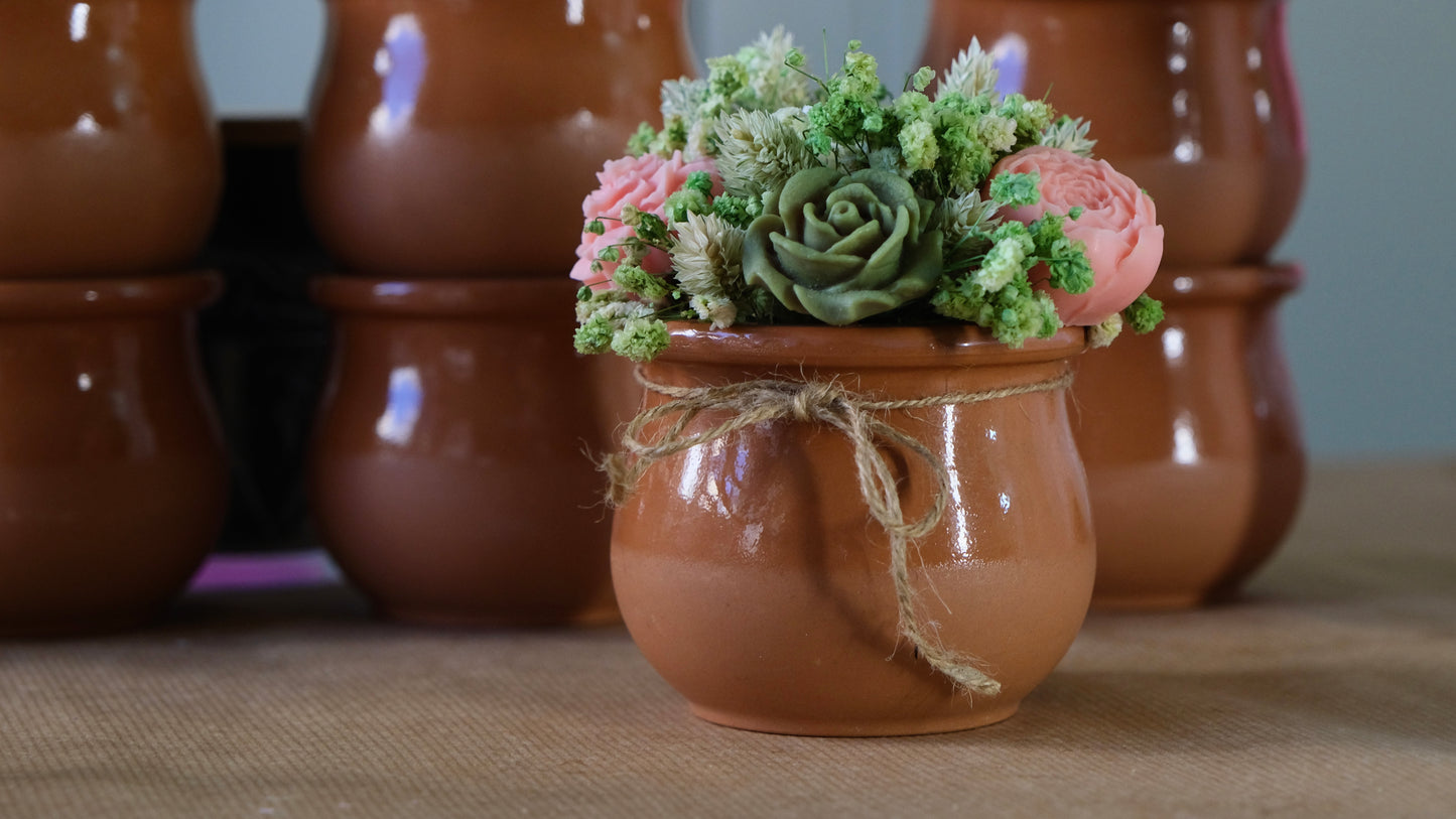 Green and pink rose candle bouquet in clay pot
