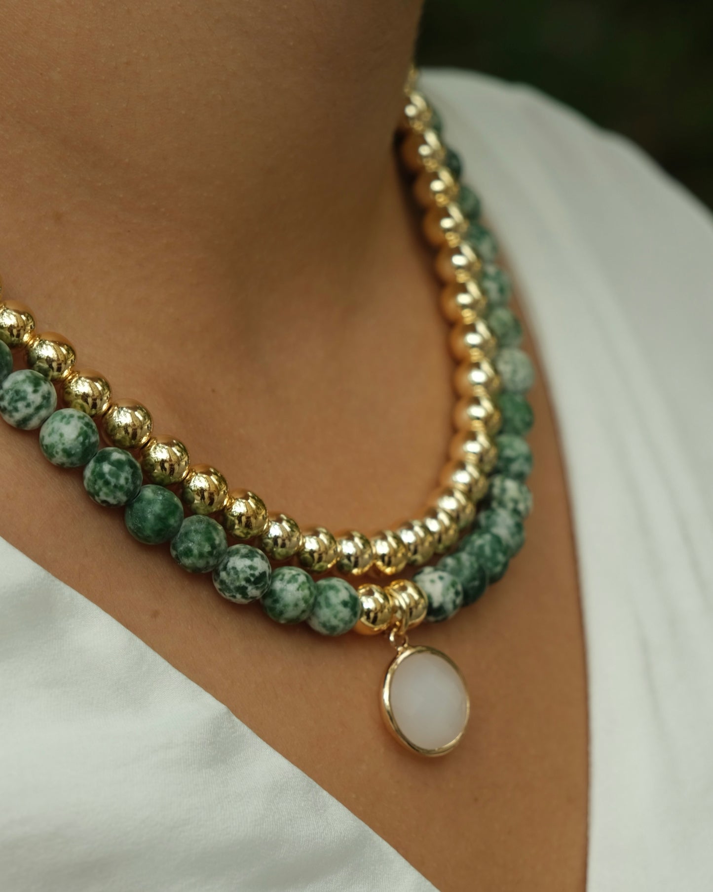 Green and gold beaded necklace with white pendent