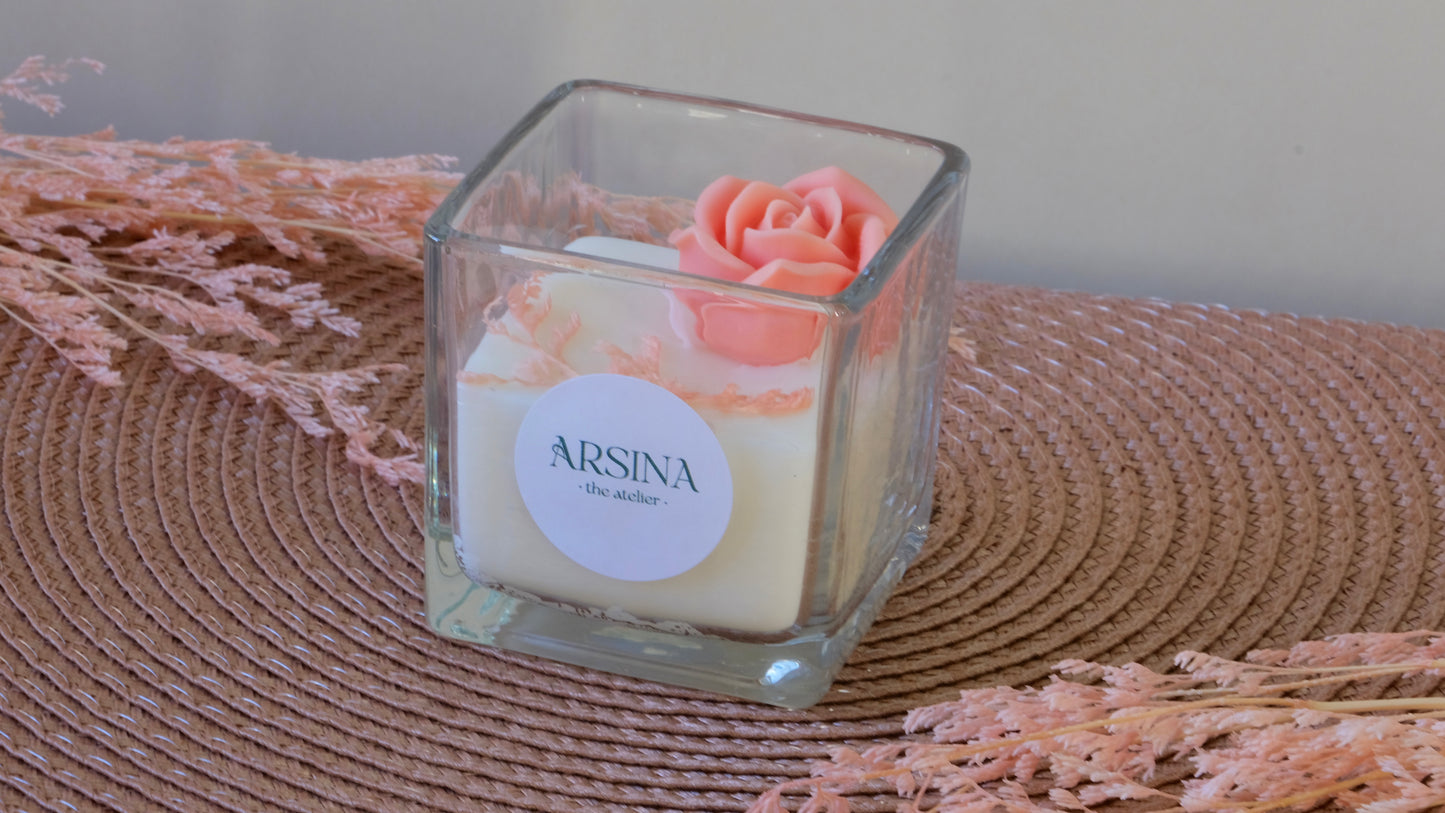 Square transparent candle jar with white candle, a blush rose on top
